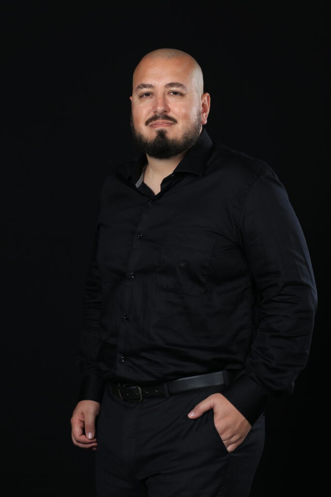 Psicólogo Lucas Rodrigues - Atendimenton online e presencial em Florianópolis e Região psicologo Lucas usando roupas pretas com um fundo preto. ele sorri